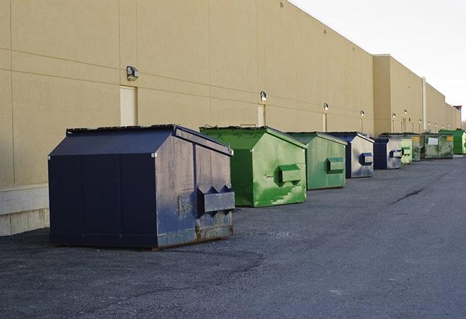 a construction worker unloading debris into a blue dumpster in High Bridge